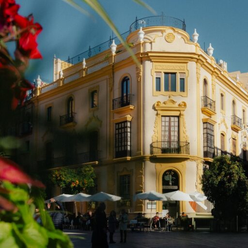 Ornate building with outdoor cafe seating in sunlight.